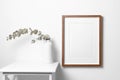 Portraut picture frame mockup on white wall with dry eucalyptus twig decoration in minimalistic interior