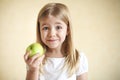 Little funny blonde girl with green apple