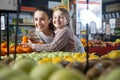 Portret beautiful blonde girl with mother choosing mandarins at