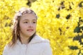 Portret of smiling little girl with handmade hair wreath on yellow Forsythia blossom background Royalty Free Stock Photo