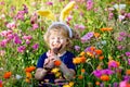 Portriat of adorable, charming toddler girl with Easter bunny ears eating chocolate bunny figure in flowers meadow