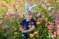 Portriat of adorable, charming toddler girl with Easter bunny ears in flowers meadow. Smiling happy baby child on sunny