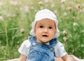 Portriat of adorable, charming toddler girl in flowers meadow. Smiling happy baby child on summer day with colorful flowers,