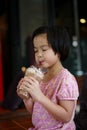 Portriat Asian little girl drinking blended ice chocolate with funny face. Happy girl enjoy eating soft drink with big smile Royalty Free Stock Photo