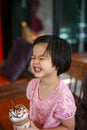 Portriat Asian little girl drinking blended ice chocolate with funny face. Happy girl enjoy eating soft drink with big smile Royalty Free Stock Photo