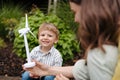 Portriat of cute boy holding wind turbine, while father charging their electric car on the street.