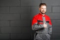 Portriat of smiling man wearing overalls near brick wall