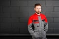 Portriat of smiling man wearing overalls near brick wall