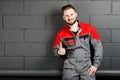 Portriat of smiling man wearing overalls near brick wall