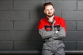 Portriat of smiling man wearing overalls near brick wall