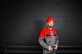 Portriat of smiling man wearing overalls near brick wall and eye