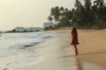 Portriat of young beautiful woman wearing a red dress standing on a tropical beach near sea