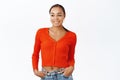 Portrit of smiling young woman in red blouse, looking aside at logo, copy space, standing over white background