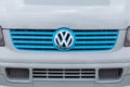 A close up of the blue front grill on a Volswagen camper van showing a VW badge