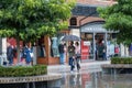 A couple take shelter from the rain under an umbrella whild walking past shop windows at a