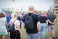 A couple wearing backpacks walking through a crowd at an outdoor festival