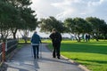 An elderly woman using through a park using walking sticks or crutches with her adult son