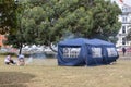 A family having a barbeque in the park with a gazebo or tend as a shelter