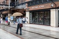 A man sheltering from the rain under an umbrella at a shopping centre Royalty Free Stock Photo