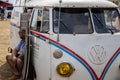 A man sitting in the side door of a rusty volkswagen camper van