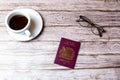 02-08-2021 Portsmouth, Hampshire, UK a Maroon British passport laid on a wooden table next to a coffee and a pair of glasses Royalty Free Stock Photo