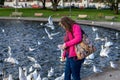 A middle aged woman feeding birds at a duck pond in the park