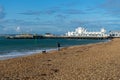 10/09/2019 Portsmouth, Hampshire, UK A middle aged woman walking her dog on a pebble beach with south parade pier southsea in the Royalty Free Stock Photo