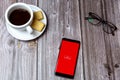 02-24-2021 Portsmouth, Hampshire, UK A mobile phone or cell phone on a wooden table with the Economist app open next to a coffee Royalty Free Stock Photo