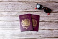 02-08-2021 Portsmouth, Hampshire, UK a pair Of British passports laid on a wooden table next to a pair of sunglasses Royalty Free Stock Photo