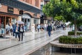 Shoppers walking through the rain at a shopping centre passing shop windows