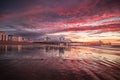 South parade pier in Southsea, Hampshire with a bright red sunrise reflecting in wet sands