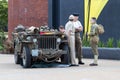 Three men in authentic world war two military uniforms next to an american army jeep from the Royalty Free Stock Photo