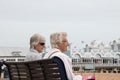 Two elderly ladies or women sat on a bench talking at the english seaside