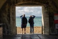 10/09/210/09/2019 Portsmouth, Hampshire, UK two men stood in an archway at the beach looking out to sea shading their eyes from