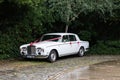 A white rolls royce with ribbons ready to be used as a wedding car