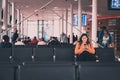 04/04/2020 Portsmouth, Hampshire, UK a young woman looking at her phone with headphones in smiling while seated waiting a a