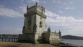 Portugal, Lisbon - July 17, 2022: Medieval tower on river bank. Action. Old white tower stands on river bank on sunny