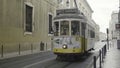 Portugal, Lisbon - July 29, 2022: Small tram passing on narrow street. Action. Small tram rides along narrow street of