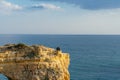Portuguese coast line with Elephant Shaped Cliff in Algarve during the Sunset, Two people sitting on the cliff, Portugal