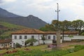 Portuguese colonial style houses, flowered garden square. In the background mountain. Historic city of Catas Altas in Minas Gerais