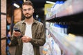 Posiive male customer choosing new shampoo in supermarket hair section Royalty Free Stock Photo