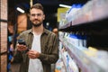 Posiive male customer choosing new shampoo in supermarket hair section Royalty Free Stock Photo