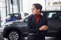 Posing for the camera. Young business man in luxury suit and formal clothes is indoors near the car Royalty Free Stock Photo