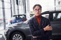 Posing for the camera. Young business man in luxury suit and formal clothes is indoors near the car Royalty Free Stock Photo