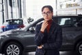 Posing for the camera. Young business man in luxury suit and formal clothes is indoors near the car Royalty Free Stock Photo