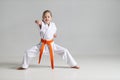 Position for defense in karate, training of a little girl in a kimono on a white background