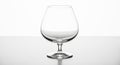 Empty Clear Glass Brandy Snifter on a Reflective Surface with White Background Royalty Free Stock Photo