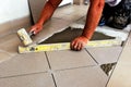 positioning large ceramic floor tiles during flooring installation with level and mallet. closeup view.