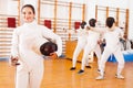 Positive young female fencer standing at fencing workout