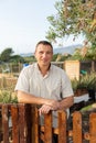 Positive adult amateur gardener standing near wooden fence at smallholding Royalty Free Stock Photo